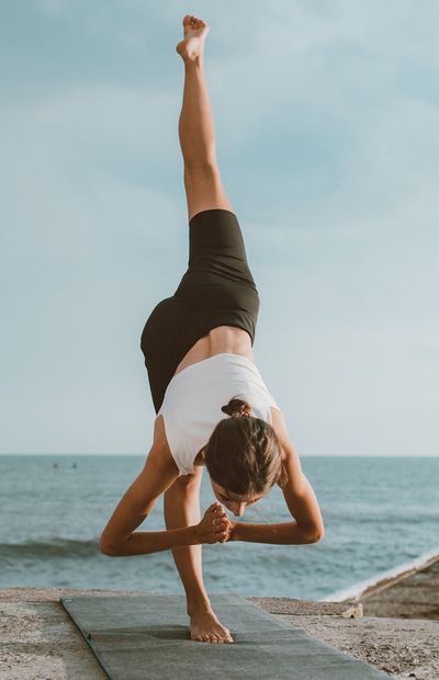 Tall image showing a person in a balanced standing yoga pose.